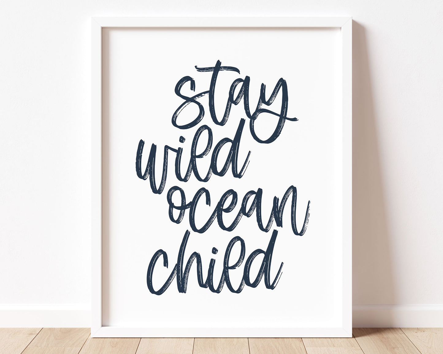 Neutral Tan Stay Wild Ocean Child Printable Wall Art featuring a textured brush style cursive lettered quote in a navy blue color.