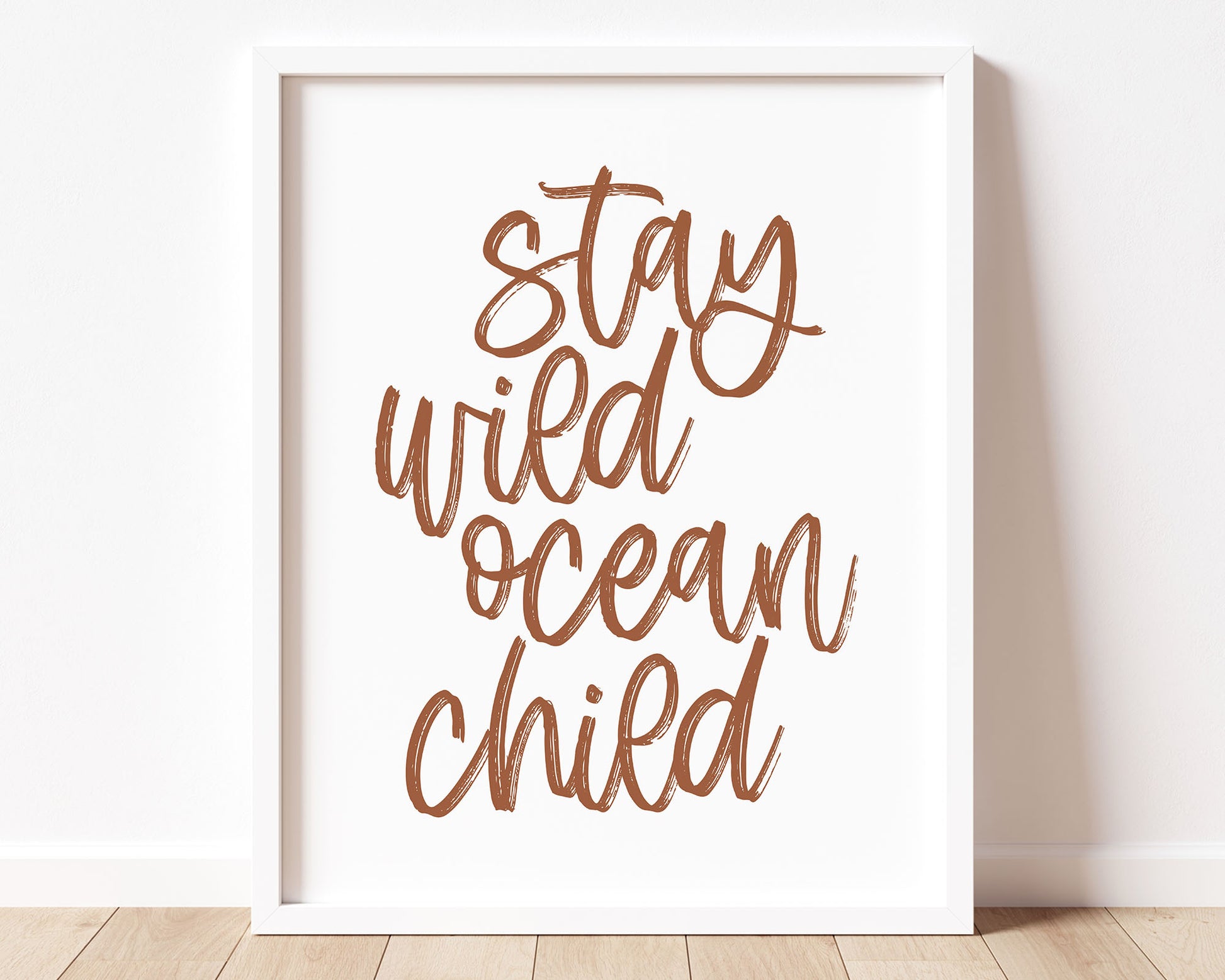 Neutral Tan Stay Wild Ocean Child Printable Wall Art featuring a textured brush style cursive lettered quote in a rusty, earth toned clay terracotta color.